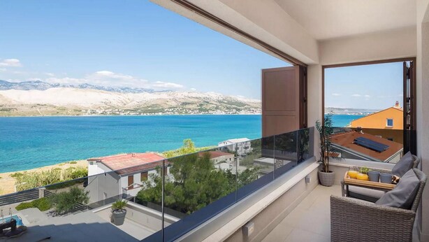 Een balkon met uitzicht op zee en bergen.