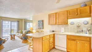 A kitchen with wooden cabinets, a dishwasher, and a dining area with wicker chairs and a glass table.
