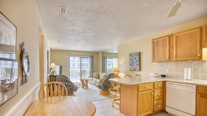 A spacious kitchen with wooden cabinets, a dishwasher, and a dining area with a wooden table and chairs.