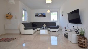 Een moderne woonkamer met een modulaire bank, een salontafel, een televisie en een groot raam.