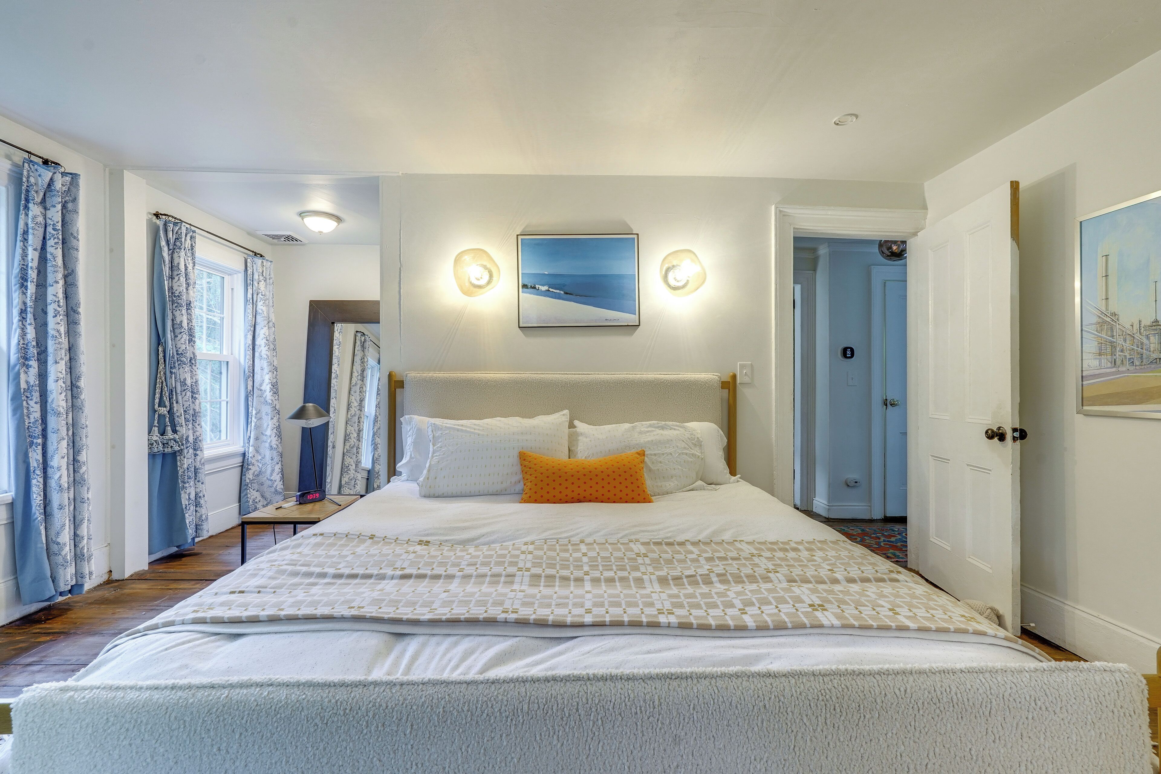A bedroom with a bed, a nightstand, a lamp, and a painting on the wall.
