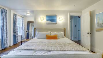 A bedroom with a bed, a nightstand, a lamp, and a painting on the wall.