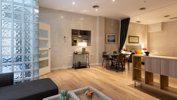 Un salon moderne avec une table basse en verre, un canapé et un coin repas comprenant une table et des chaises.