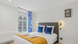 A modern hotel room with a large bed, a window with a view, and a wall-mounted light fixture. - L’escale 1 - Modern Getaway in the Heart of Honfleur (Honfleur)