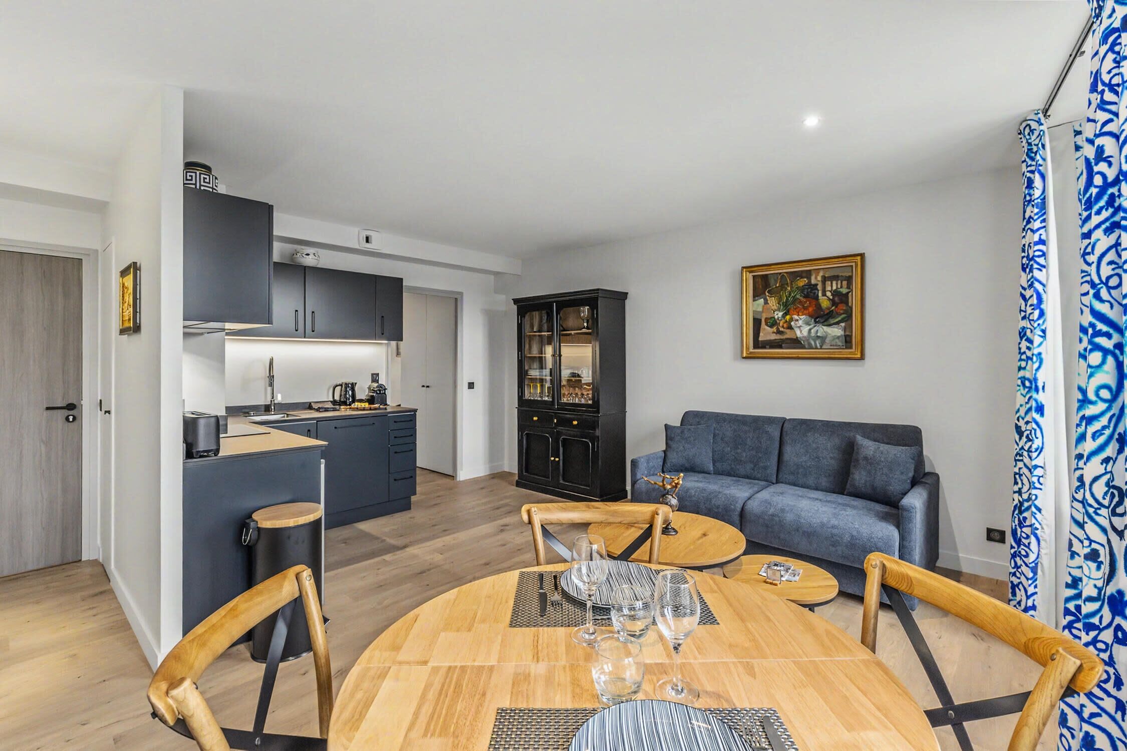A modern living space with a dining area, kitchen, and a sofa.