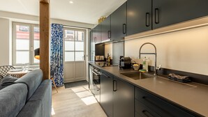 Une cuisine moderne avec des meubles de couleur sombre, un plan de travail en acier inoxydable et un four encastré.