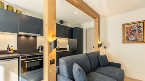 Une cuisine moderne avec des meubles de rangement de couleur sombre, un four encastré et un réfrigérateur.