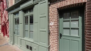 A building facade with green doors and windows, brick walls, and a traditional design. - L'Escale du Vieux Port 4P - Closed Garage - Sauna - Air Conditioning (Honfleur)