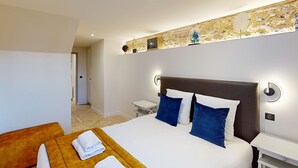 A hotel room with a large bed, two pillows, a bedside table, and a wooden bench with towels. - L'Escale du Vieux Port 4P - Closed Garage - Sauna - Air Conditioning (Honfleur)