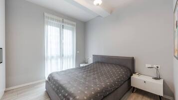 A modern bedroom with a large bed, a bedside table, a nightstand, and a ceiling light fixture.
