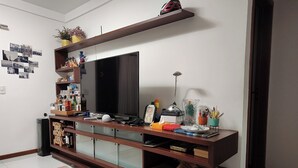 Una sala de estar moderna con un televisor de pantalla plana grande, un mueble bajo de madera y varios objetos decorativos.