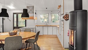 A modern kitchen with white cabinets, a central island, and a large stove. - 4 bedroom cozy home in Væggerløse (Væggerløse)