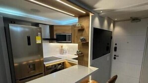 Una cocina moderna con una isla central, electrodomésticos de acero inoxidable y un televisor de pantalla plana en la pared.
