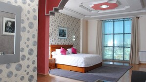 A hotel room with a large bed, a nightstand, a framed picture on the wall, and a window with curtains. - Maraval Hotel Oran (Oran)