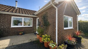 A brick house with a tiled roof, a front porch, and potted plants. - Charming retreat – Near the Sea & Pendine Sands (Pendine)