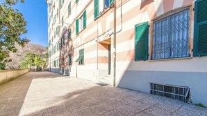 Um edifício com fachada listrada, persianas verdes e chão em mosaico.