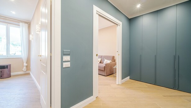A spacious room with a light wooden floor, a large wardrobe, and a door leading to another room. - Santa Maria Delle Vigne Charming Apt X4 Book Now! (Genoa)