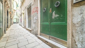 A narrow cobblestone street with a green door and a window on the right. - Santa Maria Delle Vigne Charming Apt X4 Book Now! (Genoa)