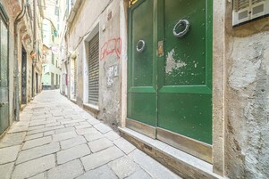 Una estrecha calle adoquinada con una puerta verde y una ventana a la derecha.