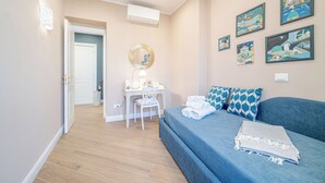 A bedroom with a bed, a desk, a chair, and a wall with framed artwork. - Santa Maria Delle Vigne Charming Apt X4 Book Now! (Genoa)