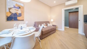 A modern living room with a dining table set for four, a brown sofa, and a large abstract painting on the wall. - Santa Maria Delle Vigne Charming Apt X4 Book Now! (Genoa)