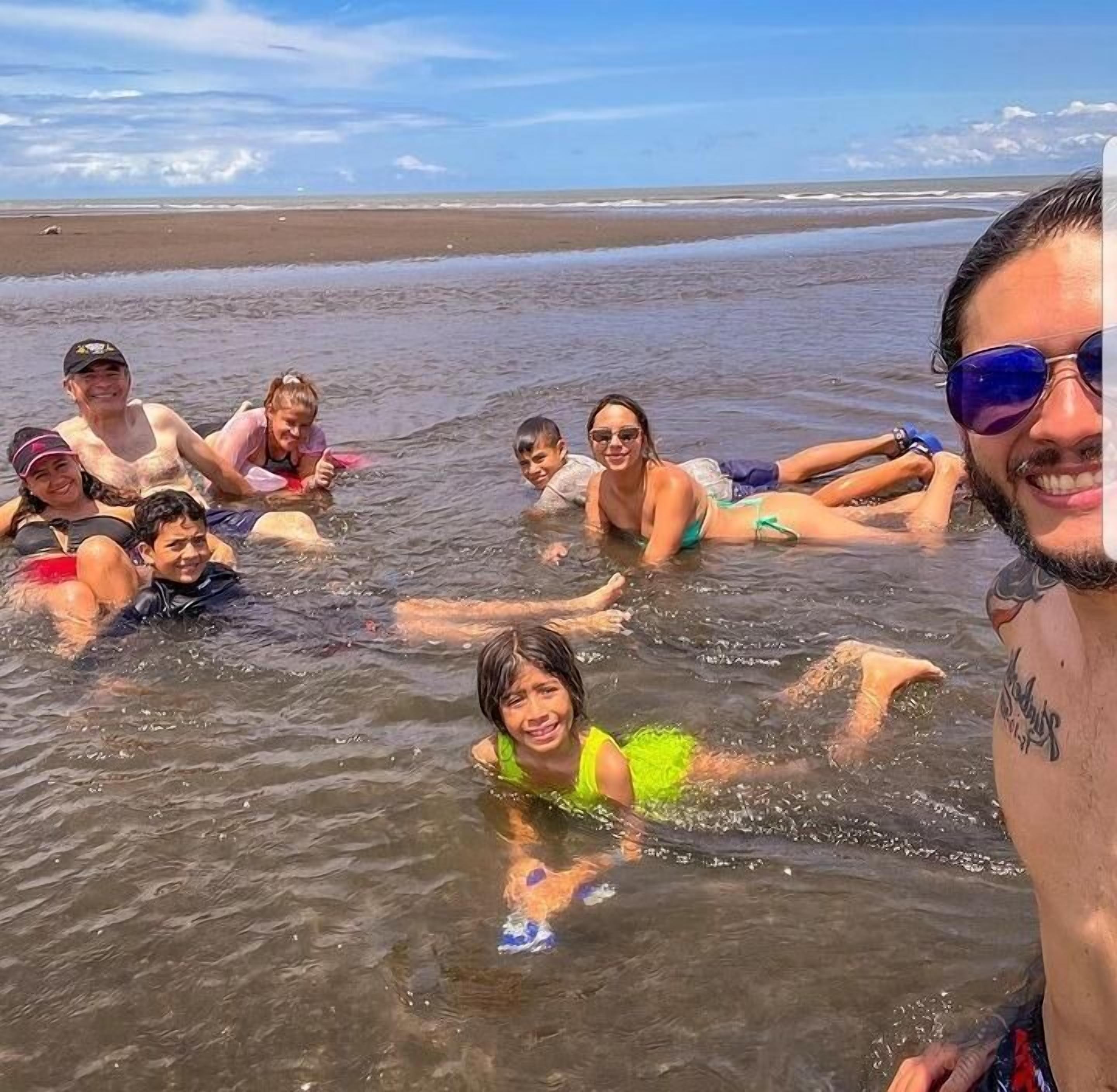 A group of people in a shallow water area on a beach.