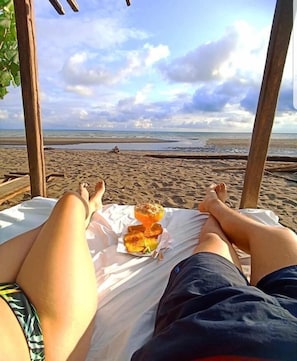 Escena de playa con una persona acostada en una silla de playa, mirando al océano.