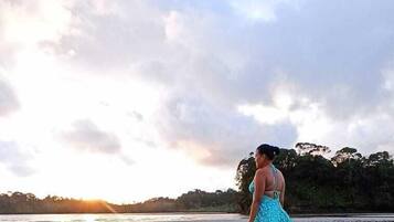A person walking on a beach with a sunset in the background.