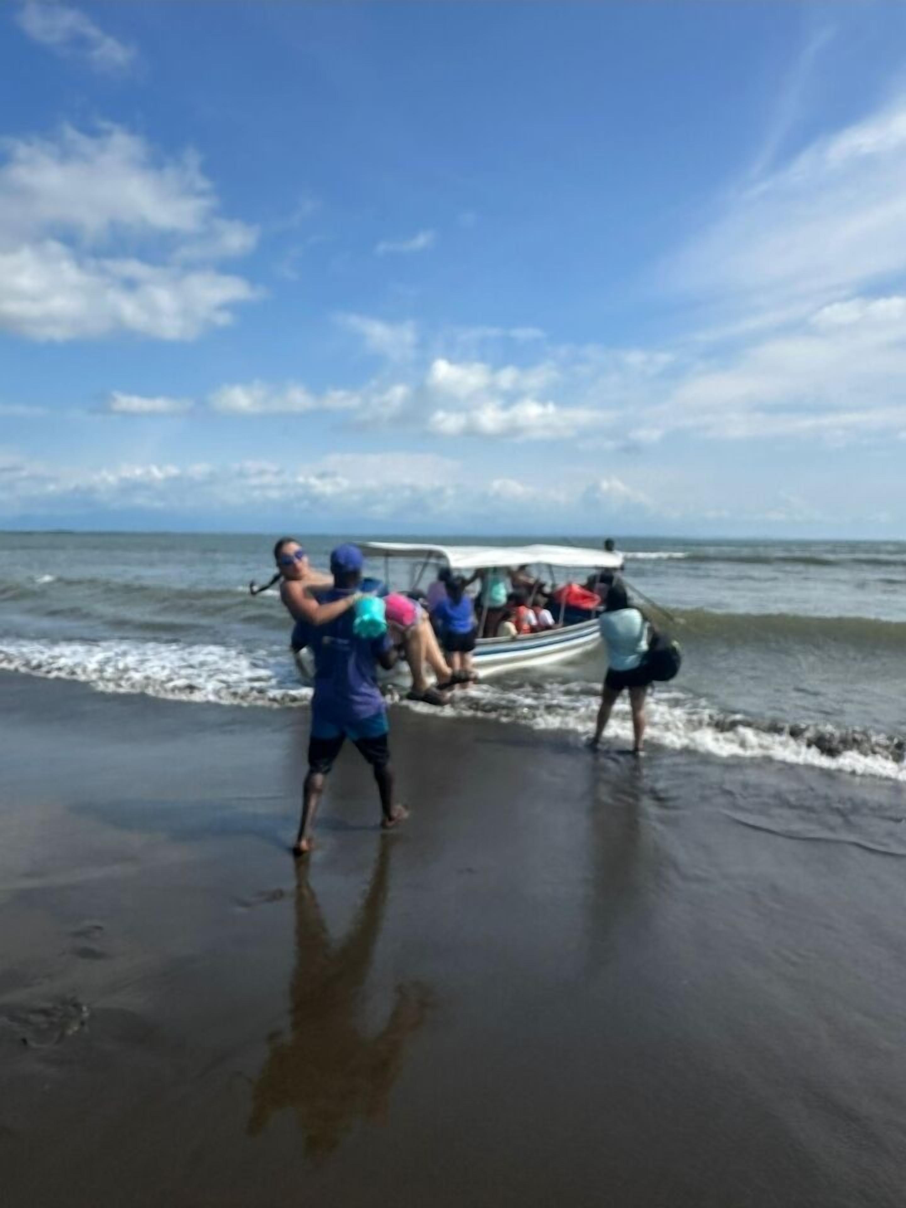 A beach scene with a boat carrying people.