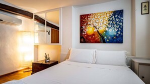 A hotel room with a bed, a bedside lamp, a painting on the wall, and a mirror. - YiD appartamento al Carmine (Firenze)