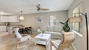 A modern living space with a dining area, a sofa, and a ceiling fan. - Beach Retreat: Walk to Lantana Dining & Shops (Lantana)