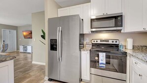A modern kitchen with stainless steel appliances, white cabinetry, and a granite countertop. - Beach Retreat: Walk to Lantana Dining & Shops (Lantana)