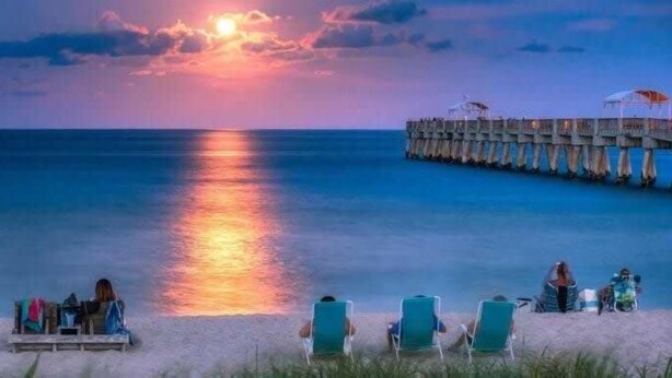 A beach scene with a pier, chairs, and a sunset. - Beach Retreat: Walk to Lantana Dining & Shops (Lantana)