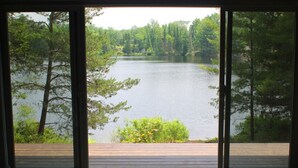 Une pièce dotée d’une grande fenêtre donnant sur un lac bordé d’arbres.