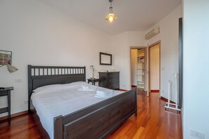 A bedroom with a wooden bed, a bedside table, a nightstand, a wardrobe, and a closet.