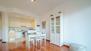 A modern kitchen with white cabinets, a dining table with chairs, and a white cabinet with glass doors. - Genoa Getaway! Sturla Comfy Flat X2 Free Parking (Genoa)