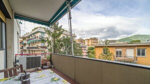 A balcony with a table set for two, a coffee pot, and cups. The balcony overlooks a residential area with buildings and a hill in the background. - Genoa Getaway! Sturla Comfy Flat X2 Free Parking (Genoa)