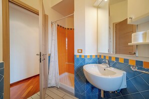 A bathroom with a shower, a sink, and a mirror.