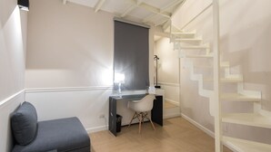 A modern room with a desk, a chair, a sofa, and a staircase. - Five Boutique Rooms (Naples)
