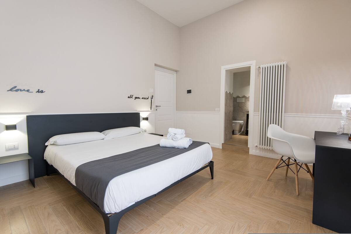Une chambre d’hôtel moderne, dotée d’un grand lit, de tables de chevet, d’un bureau et d’une chaise.