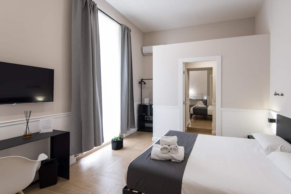 Une chambre d’hôtel moderne dotée d’un grand lit, d’un bureau, d’une télévision à écran plat et donnant sur le couloir.