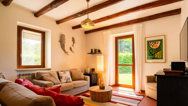 A cozy living room with a sofa, a coffee table, and a lamp. There is a bookshelf and a framed picture on the wall. - Pimpinnacolo (Monte Argentario)