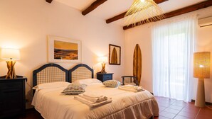 A bedroom with a bed, a nightstand, a lamp, a framed picture, and a surfboard. - Pimpinnacolo (Monte Argentario)