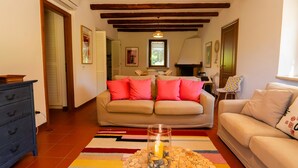 A cozy living room with a beige sofa, a white sofa, and a coffee table with a candle. There is a wooden ceiling and a window with a view. - Pimpinnacolo (Monte Argentario)