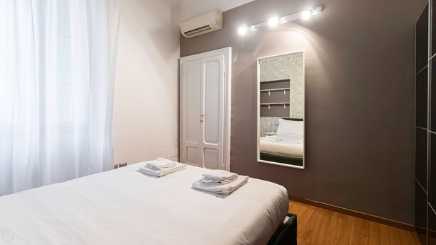 Ein Hotelzimmer mit Bett, Schrank, Spiegel und Klimaanlage.