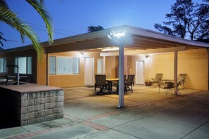 Un patio couvert avec une table et des chaises, un mur en briques et un lampadaire.
