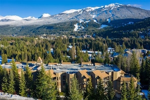 A mountain resort with multiple buildings, a ski slope, and dense forest.