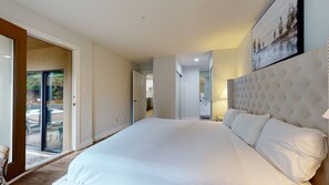 Un dormitorio con una cama grande, un ventanal corredero a un balcón y vistas al exterior.