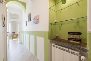 Un pasillo con una decoración en blanco y verde, un radiador, un teléfono y un cartel de bienvenida.