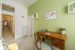 A room with a wooden desk, a chair, a world map on the wall, a radiator, and a door leading to another room. - Apartments Florence- Divina (Firenze)